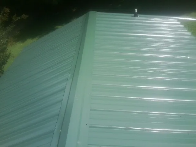 New green metal panels meeting at the ridge of a roof — Flat Roof Repair work by our crew in Boscobel