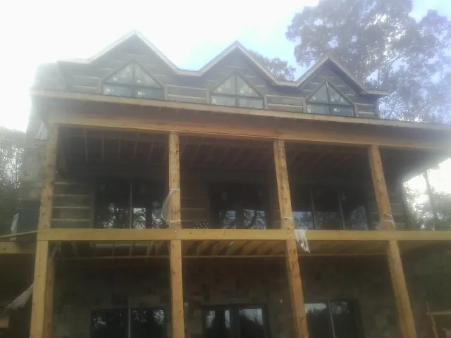 Dormers and porch framing on a large log home under construction — Roof Coating work by our crew in Boscobel