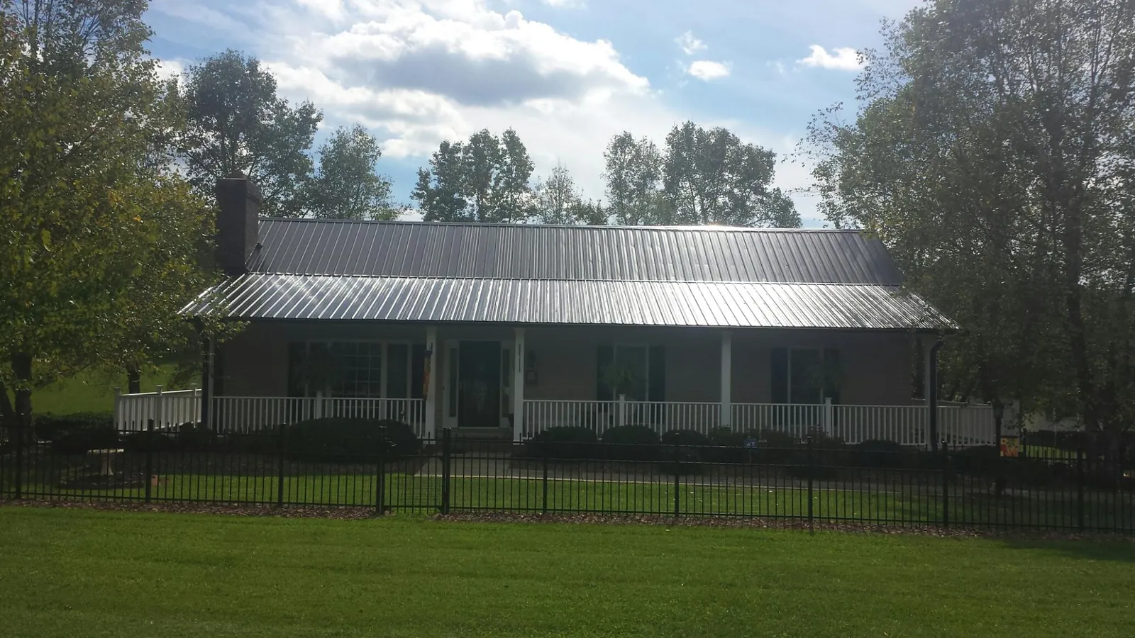 Gray metal roof on a brick ranch with a full width front porch — Gutter Guard Installation work by our crew in Boscobel