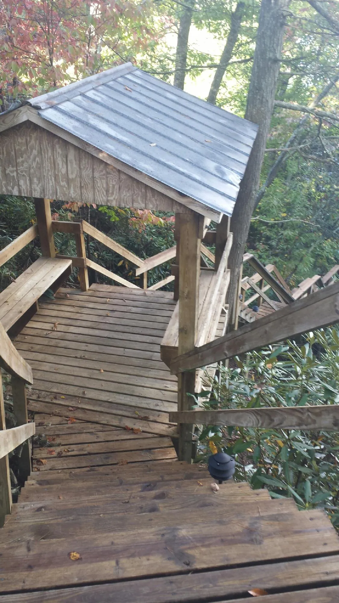 Metal roofed shelter over wooden steps on a wooded walkway — Skylight Repair & Installation work by our crew in Boscobel