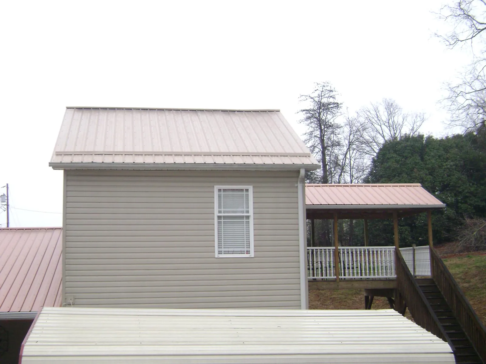 Tan metal roofs on a two story addition and attached porch, from a Roof Replacement job in Boscobel