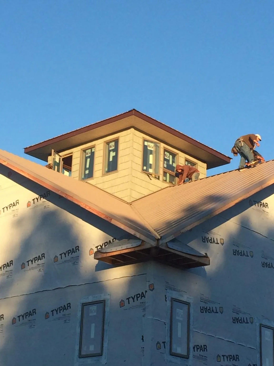 Roofers working around a rooftop cupola on a new metal roof at sunset — Roof Waterproofing in Boscobel by Roofing Brothers